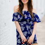 Amy Havins wears a blue off the shoulder dress with flat sandals.