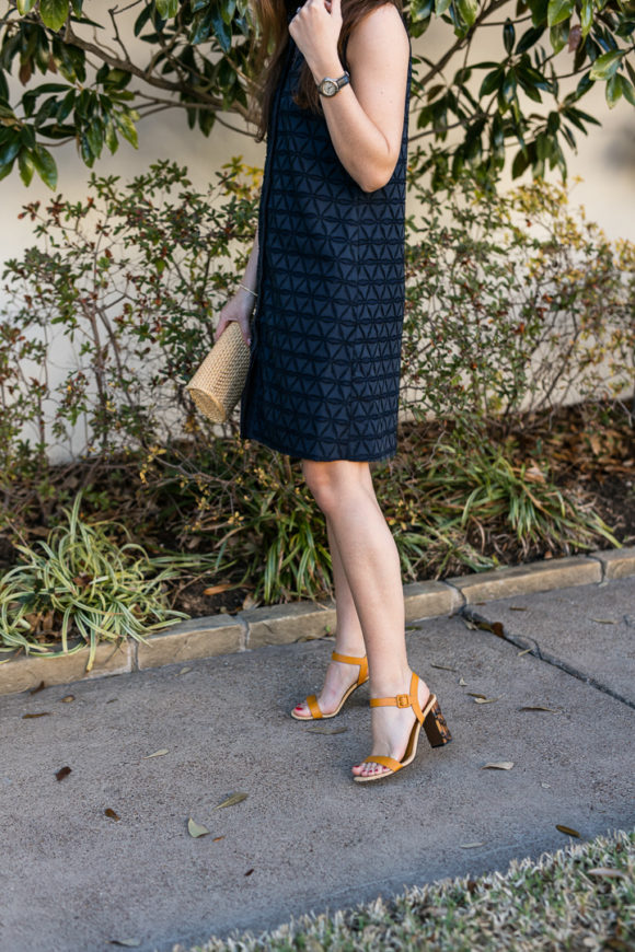 Amy havins wears a navy shift dress and spring sandals.