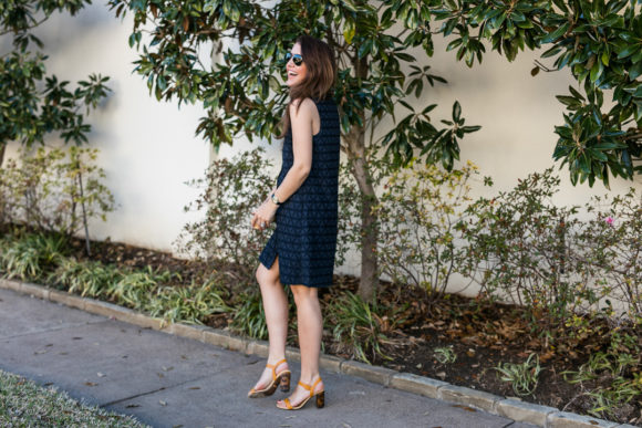 Amy havins wears a navy shift dress and spring sandals.