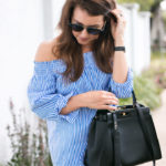 Amy Havins wears a blue and white off the shoulder blouse and white shorts.