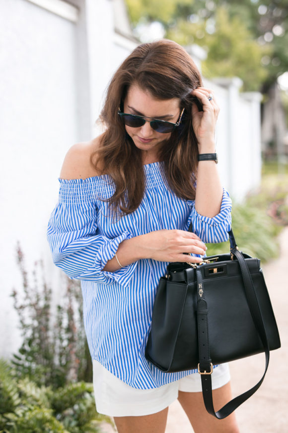 Amy Havins wears a blue and white off the shoulder blouse and white shorts.