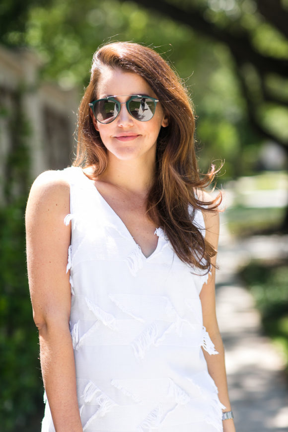 Amy Havins wears a white shift dress and neutral sandals.