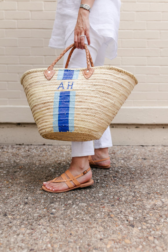 Amy Havins wears white jeans and a white blouse with statement earrings.