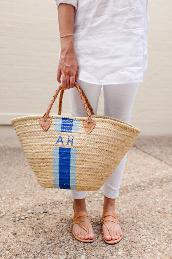 Amy Havins wears white jeans and a white blouse with statement earrings.