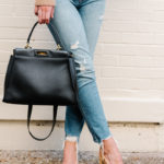 Amy Havins wears ripped jeans, a camel sweater and chanel heels.