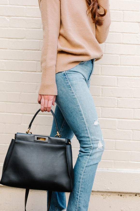 Amy Havins wears ripped jeans, a camel sweater and chanel heels.