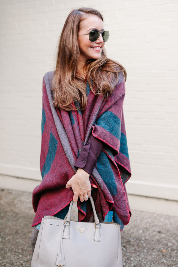 Amy Havins wears a poncho with stuart weitzman over the knee boots and jeans.