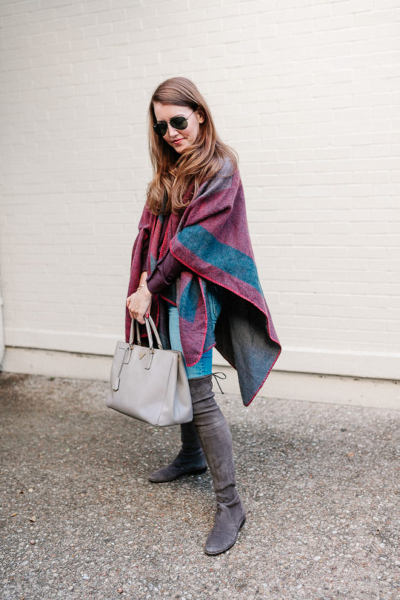 Amy Havins wears a poncho with stuart weitzman over the knee boots and jeans.