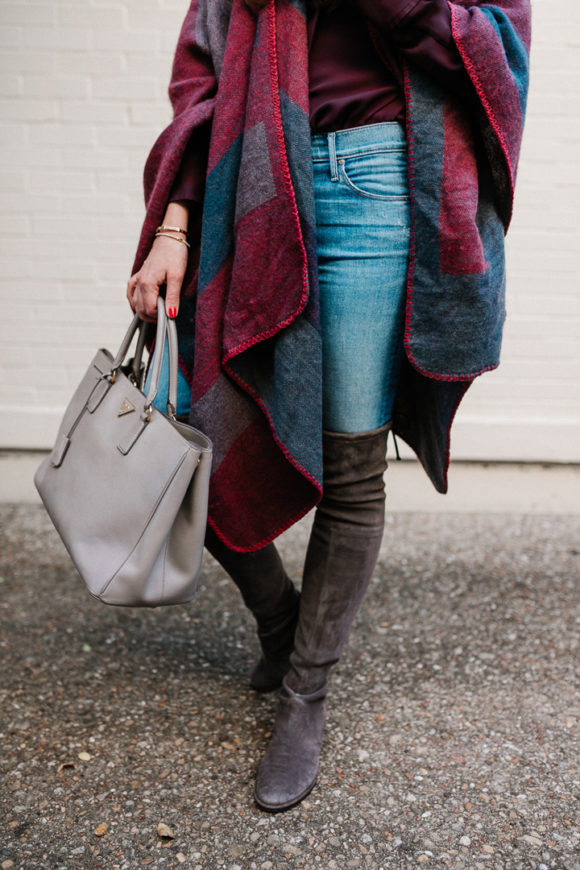 Amy Havins wears a poncho with stuart weitzman over the knee boots and jeans.