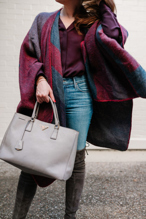 Amy Havins wears a poncho with stuart weitzman over the knee boots and jeans.