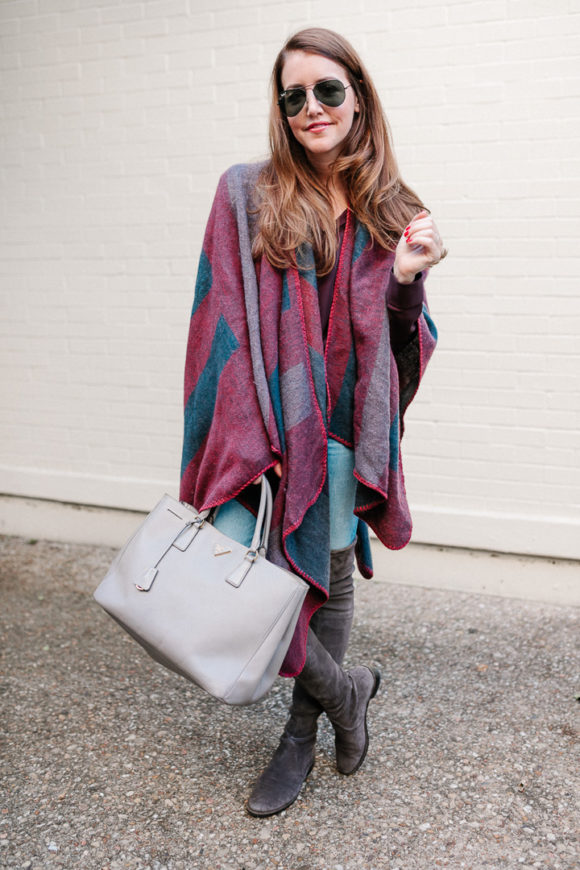 Amy Havins wears a poncho with stuart weitzman over the knee boots and jeans.