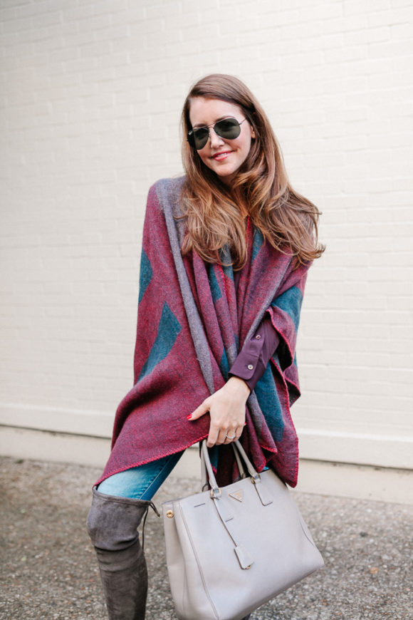 Amy Havins wears a poncho with stuart weitzman over the knee boots and jeans.