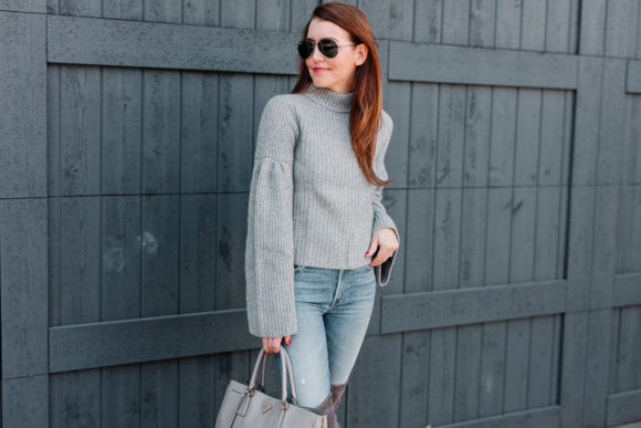 Amy havins wears a gray sweater and over the knee boots.