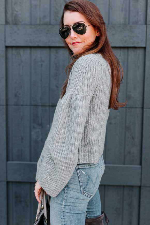 Amy havins wears a gray sweater and over the knee boots.