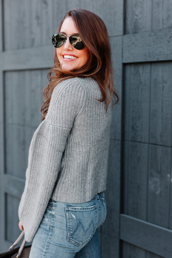 Amy havins wears a gray sweater and over the knee boots.