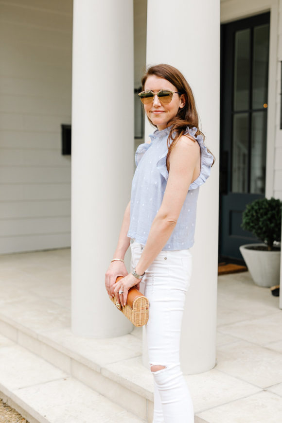 Amy Havins wears white jeans and a sleeveless ruffle blouse.