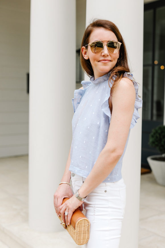 Amy Havins wears white jeans and a sleeveless ruffle blouse.