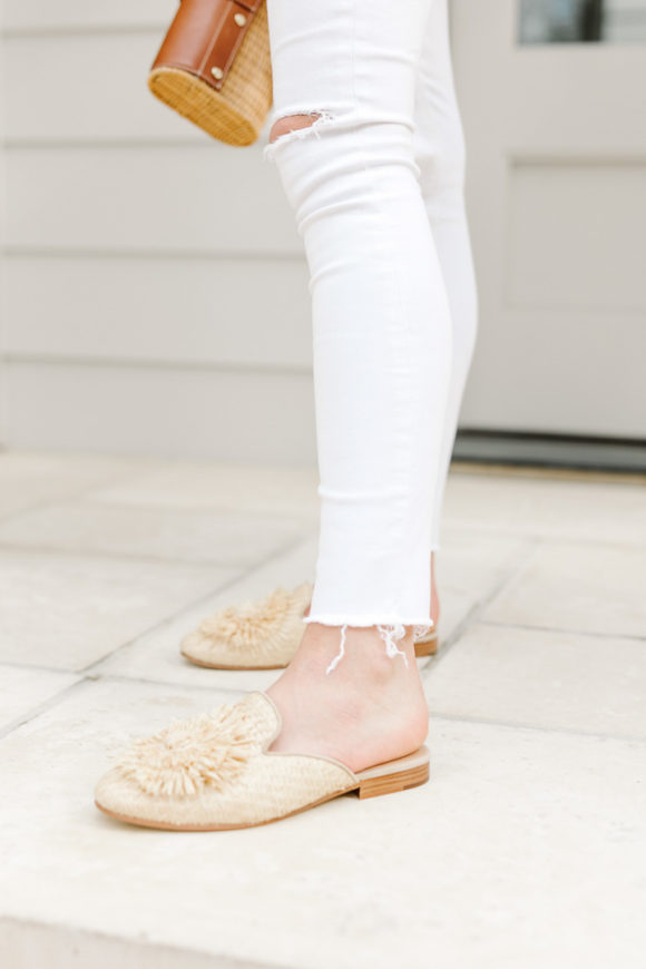 Amy Havins wears white jeans and a sleeveless ruffle blouse.