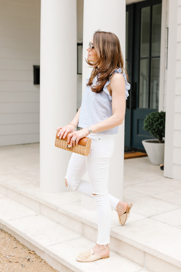 Amy Havins wears white jeans and a sleeveless ruffle blouse.