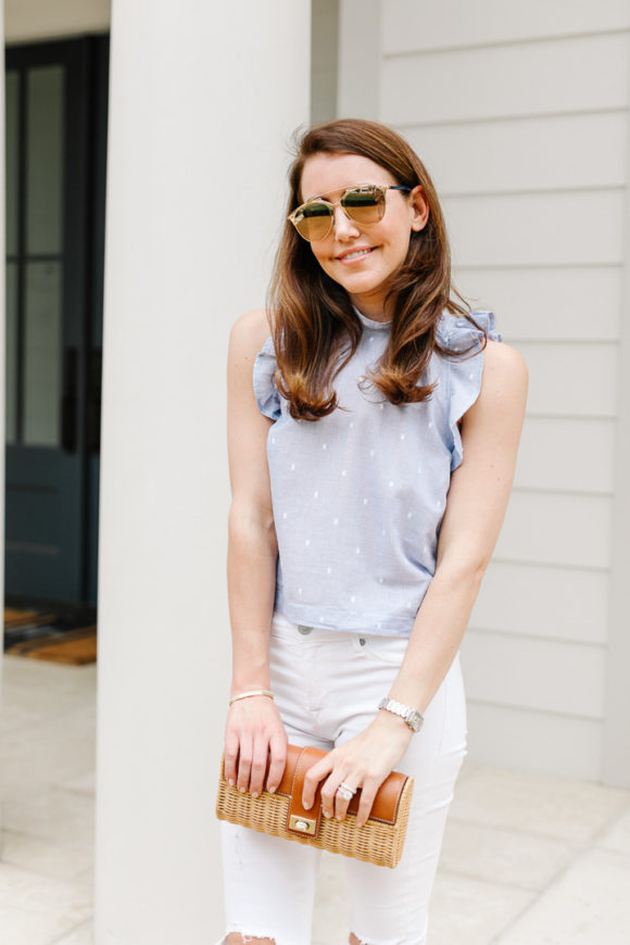 Amy Havins wears white jeans and a sleeveless ruffle blouse.